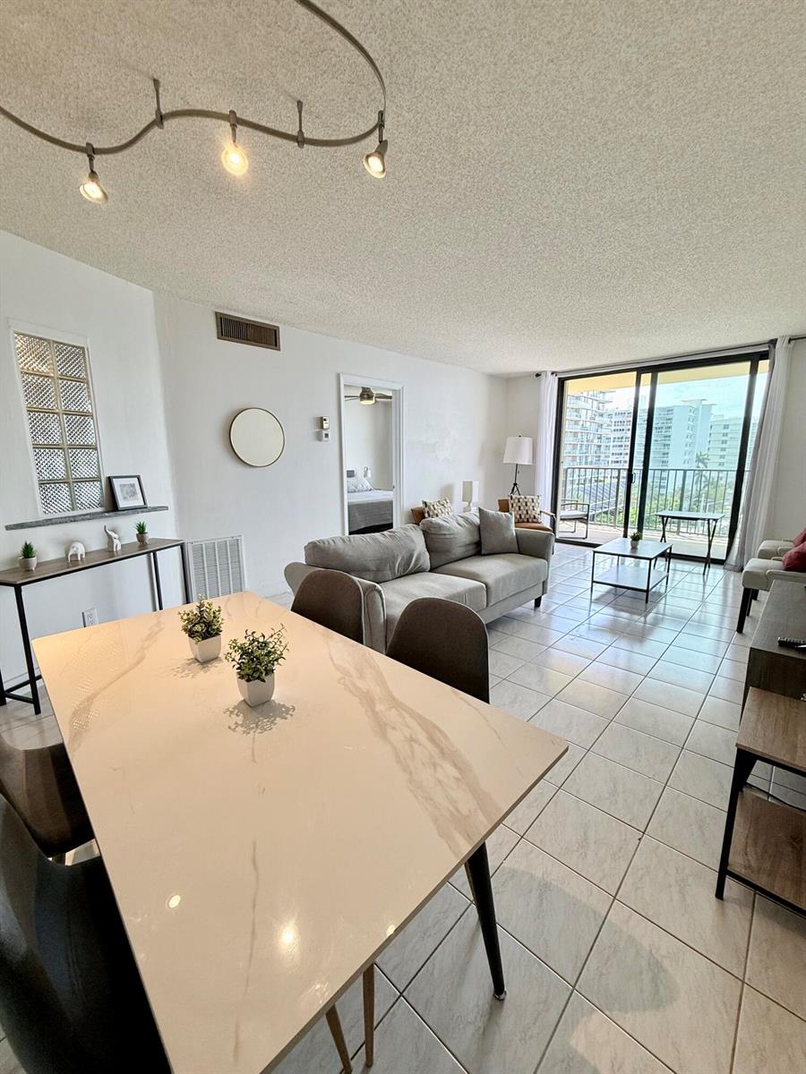 A living and dining area features tile floors, a marble-topped table, and a balcony view — 801 N Ocean Boulevard # 802, Pompano Beach FL 33062, POMPANO BEACH, FL