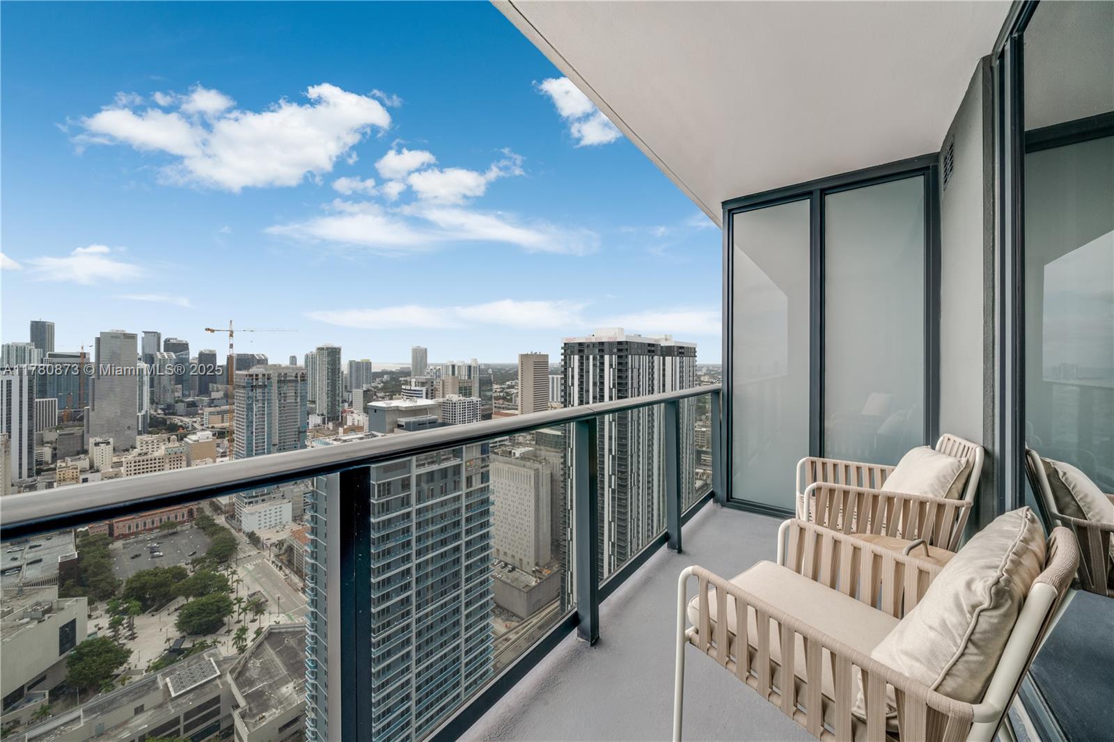 A high-rise balcony features two chairs and a panoramic view of a city skyline — 601 NE 1st Ave # 4212, Miami FL 33132, MIAMI, FL