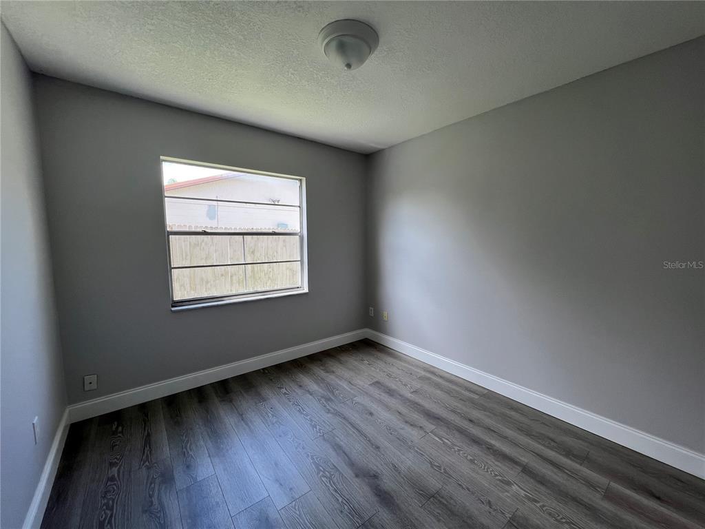 An empty bedroom features gray walls, wood-look flooring, a single window, and a ceiling light — 1313 SUMMER BREEZE ROAD, ORLANDO, FL