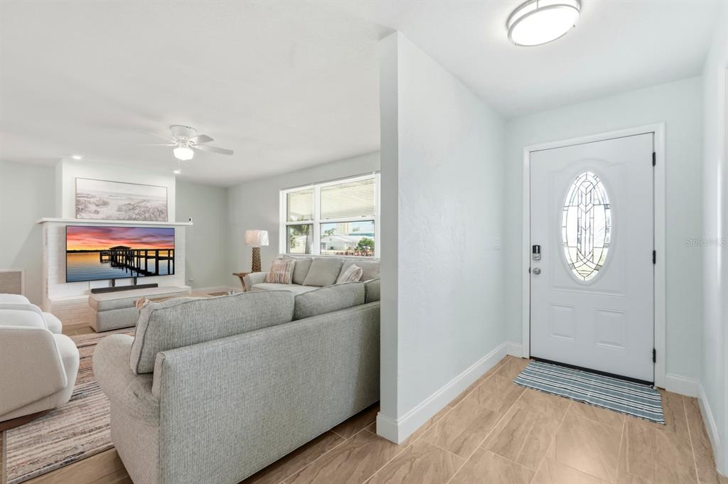 A living room with a gray sofa and a television faces a white front door — 341 PLAZA BOULEVARD, DAYTONA BEACH, FL