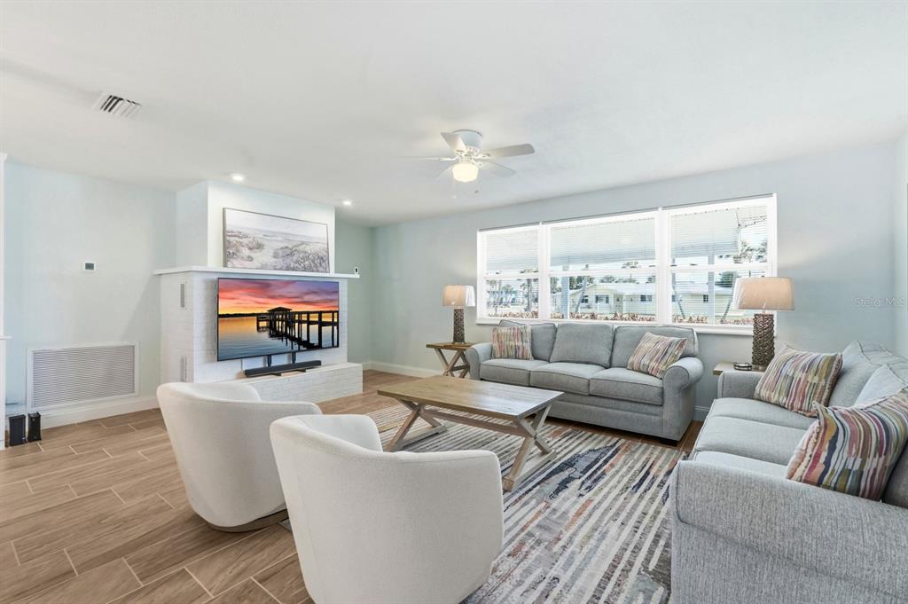 A living room with light blue walls, a white brick fireplace, and gray furniture — 341 PLAZA BOULEVARD, DAYTONA BEACH, FL