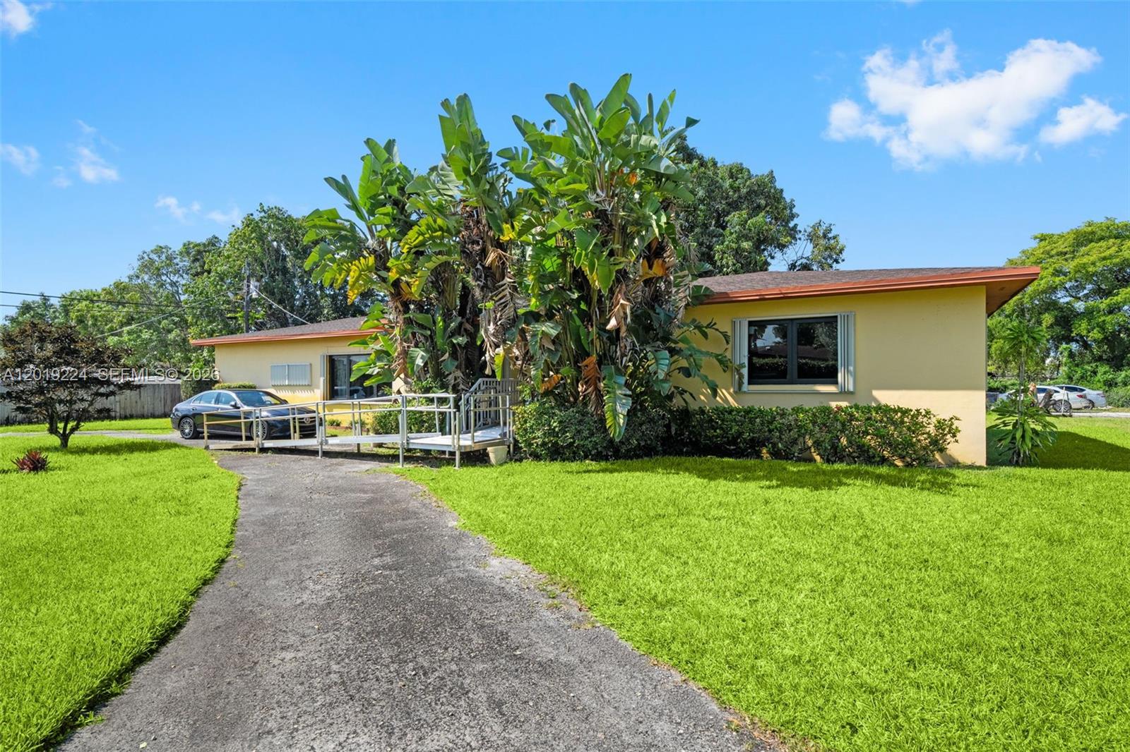 A yellow single-story house features a metal wheelchair ramp leading to the front entrance — 511 Dunad Ave, Opa-Locka FL 33054, OPA-LOCKA, FL