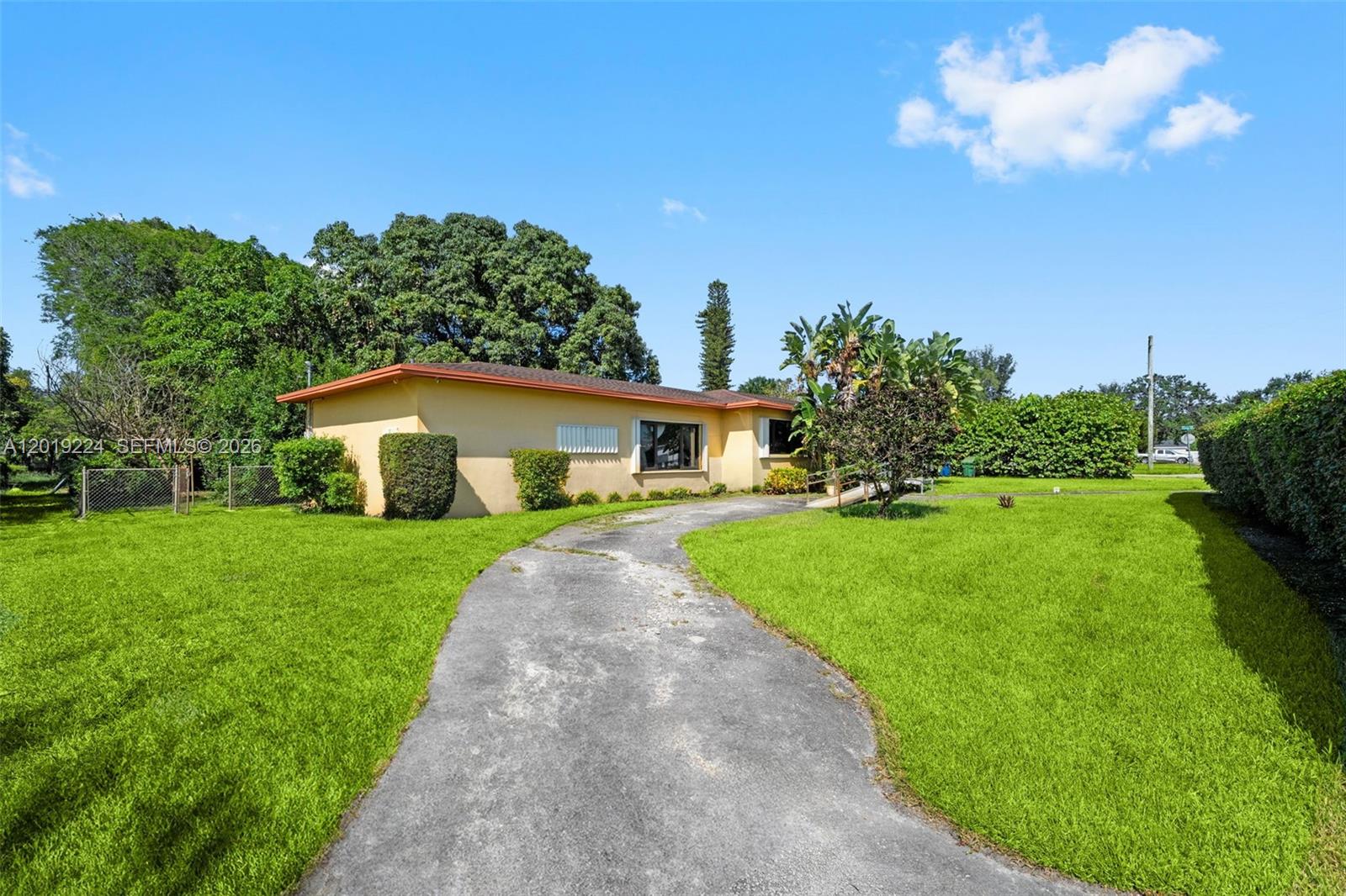 A single-story yellow house with a curved driveway sits on a large, grassy lot — 511 Dunad Ave, Opa-Locka FL 33054, OPA-LOCKA, FL