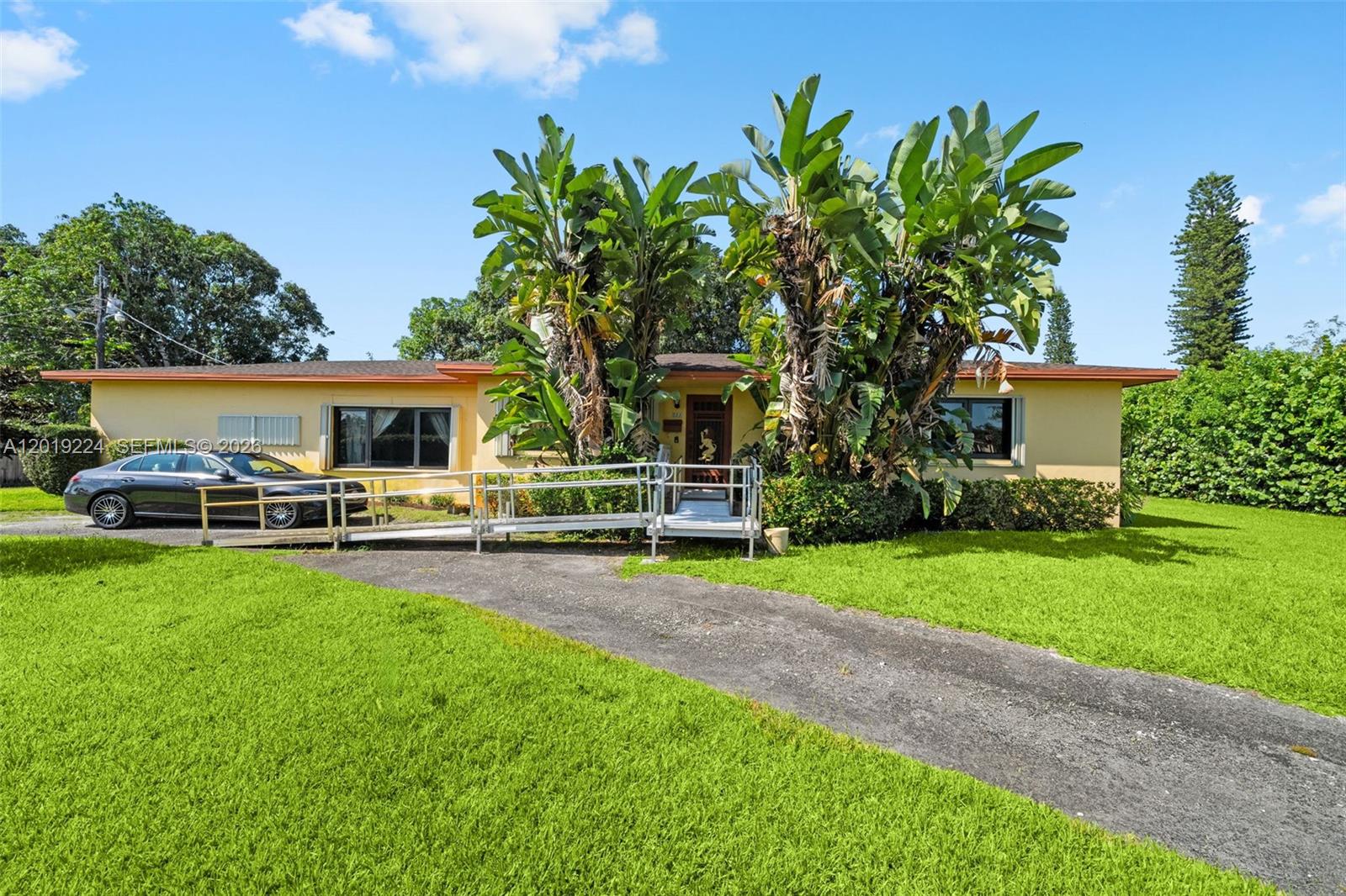 A single-story yellow house features a metal wheelchair ramp leading to the front entrance — 511 Dunad Ave, Opa-Locka FL 33054, OPA-LOCKA, FL