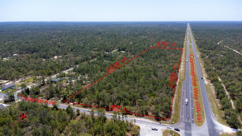 An aerial view shows a rectangular wooded lot bordered by a highway and a road — 0 THRASHER AVE, WEEKI WACHEE, FL