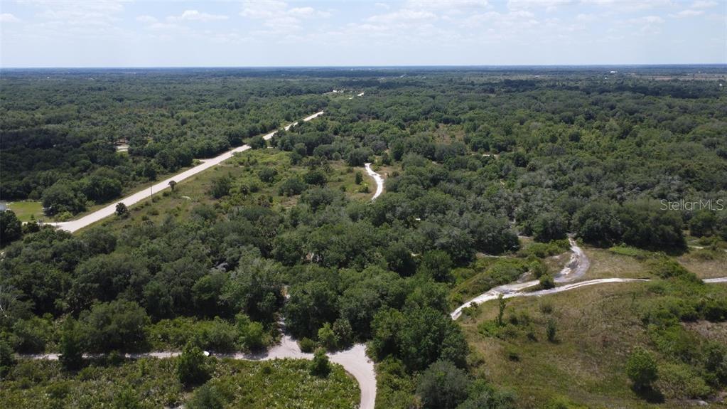 An aerial view shows a dirt road winding through a dense, wooded landscape — NW 300TH STREET, OKEECHOBEE, FL