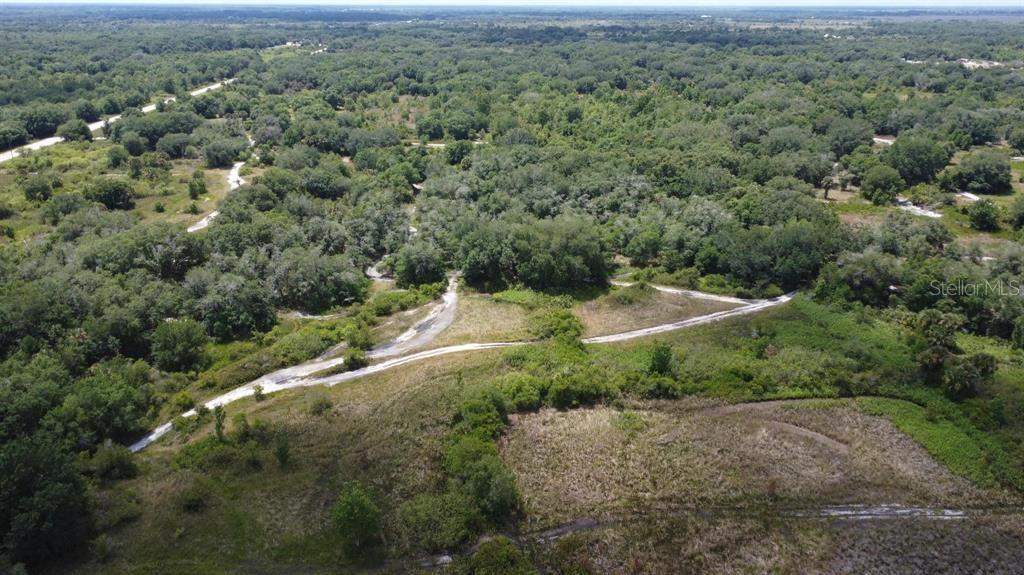 An aerial view shows a dirt path winding through a grassy, wooded landscape — NW 300TH STREET, OKEECHOBEE, FL
