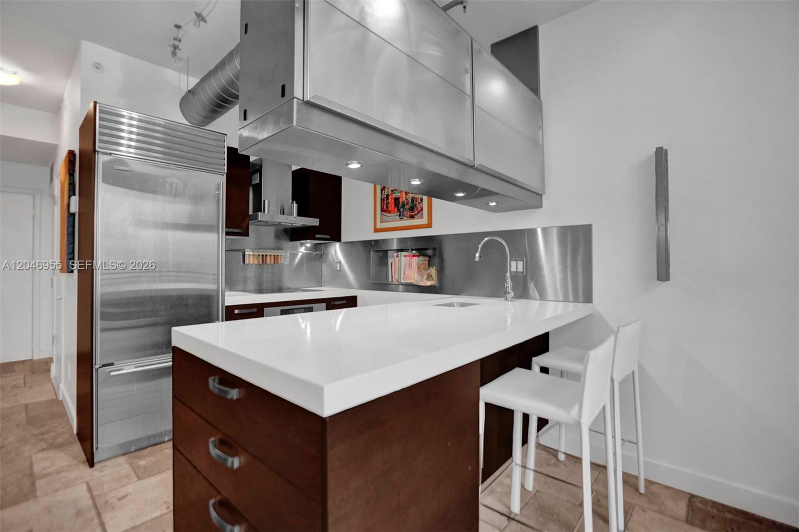 A modern kitchen features a white island, stainless steel backsplash, and dark wood cabinetry — 690 SW 1st Ct # 2707, Miami FL 33130, MIAMI, FL