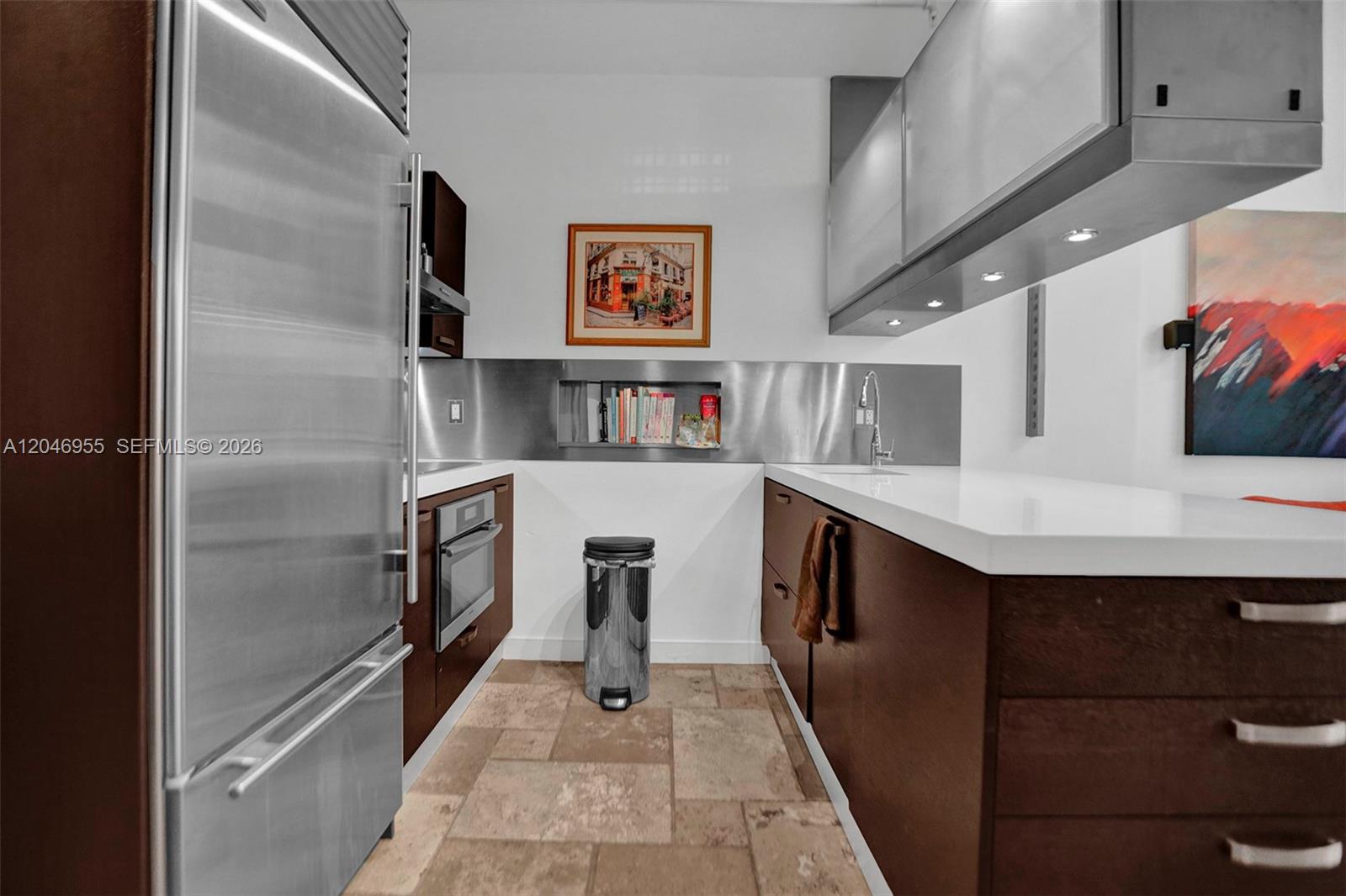 A galley kitchen features stainless steel appliances, dark wood cabinetry, and a stone tile floor — 690 SW 1st Ct # 2707, Miami FL 33130, MIAMI, FL