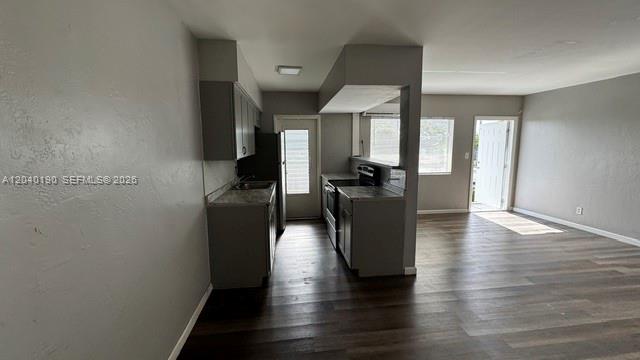 A kitchen with gray cabinets and dark wood-look flooring opens into a living area — FORT LAUDERDALE, FL