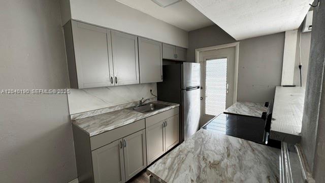 A kitchen features gray cabinets, marble-patterned countertops, and stainless steel appliances — FORT LAUDERDALE, FL