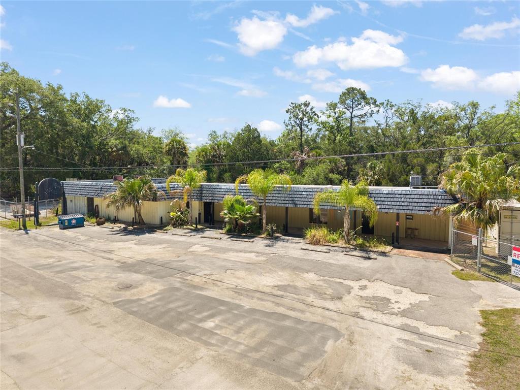 An exterior view of a single-story commercial building with a large paved parking lot — 6018 & 6024 CORTEZ BOULEVARD, WEEKI WACHEE, FL