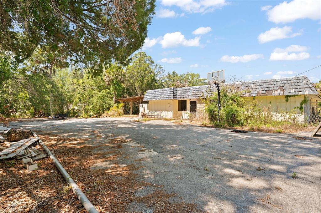 A weathered, single-story building with a basketball hoop stands on a large, paved lot — 6018 & 6024 CORTEZ BOULEVARD, WEEKI WACHEE, FL