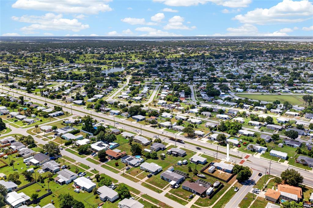An aerial view shows a residential neighborhood with a white arrow pointing to a house — 22080 MIDWAY BOULEVARD, PORT CHARLOTTE, FL