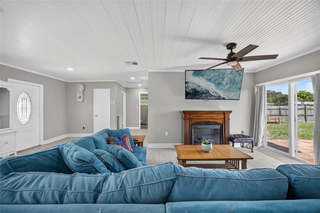 A living room features a blue sectional sofa, a fireplace with a television, and tile flooring — 22080 MIDWAY BOULEVARD, PORT CHARLOTTE, FL