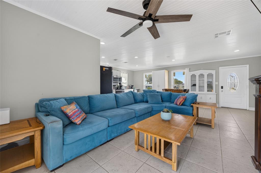 A living room features a large blue sectional sofa, a wooden coffee table, and tile flooring — 22080 MIDWAY BOULEVARD, PORT CHARLOTTE, FL
