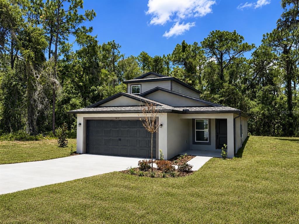 A modern, single-story house with a gray garage and a small front yard — 14117 CANADA GOOSE ROAD, BROOKSVILLE, FL