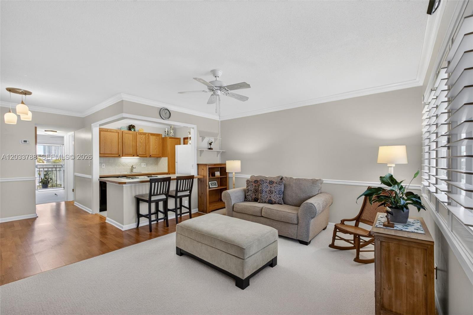 A living room with carpet, a sofa, an ottoman, and an adjacent kitchen with bar seating — 112 Doolen Ct # 306, North Palm Beach FL 33408, NORTH PALM BEACH, FL
