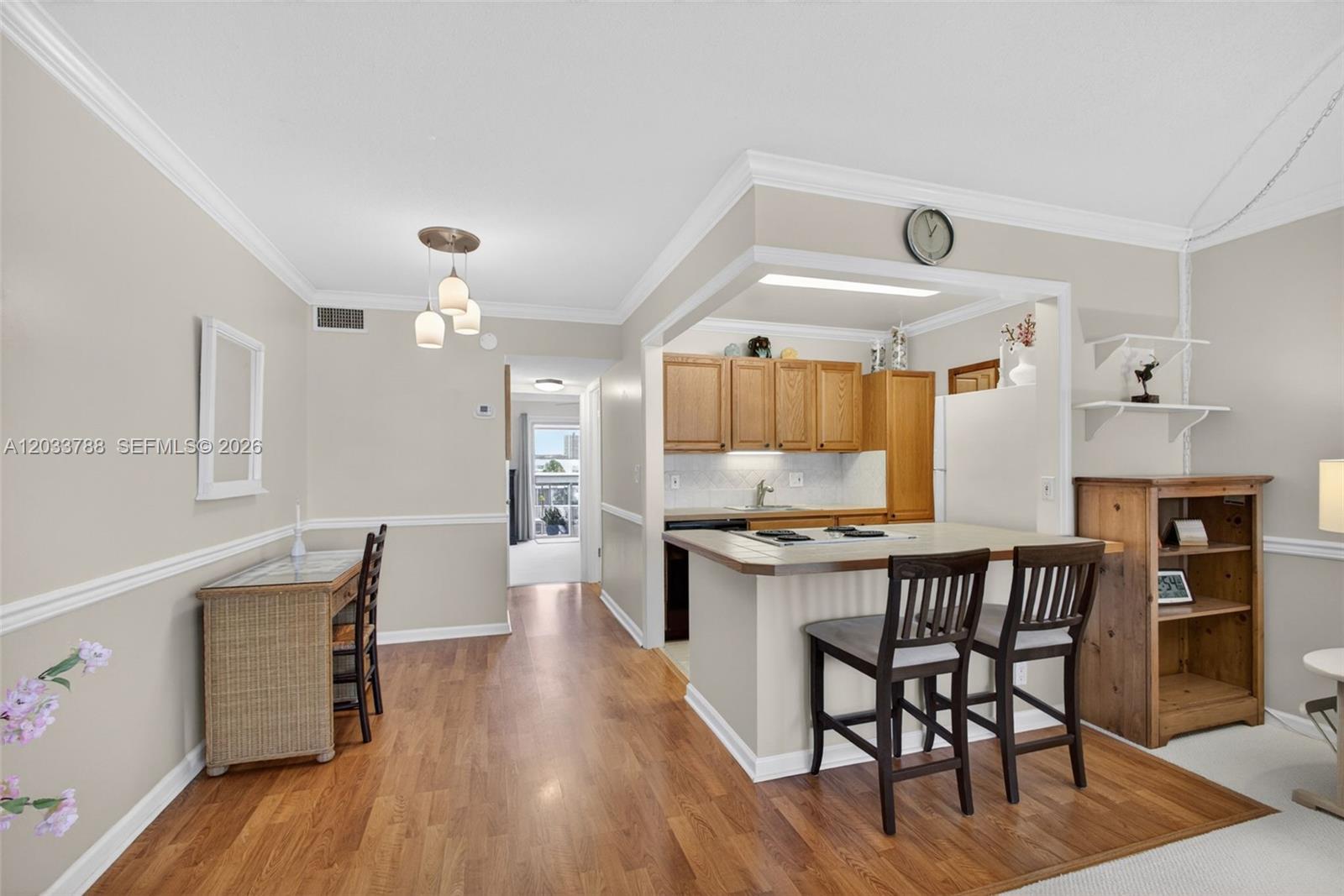 This interior view shows a kitchen with wooden cabinets and a breakfast bar — 112 Doolen Ct # 306, North Palm Beach FL 33408, NORTH PALM BEACH, FL