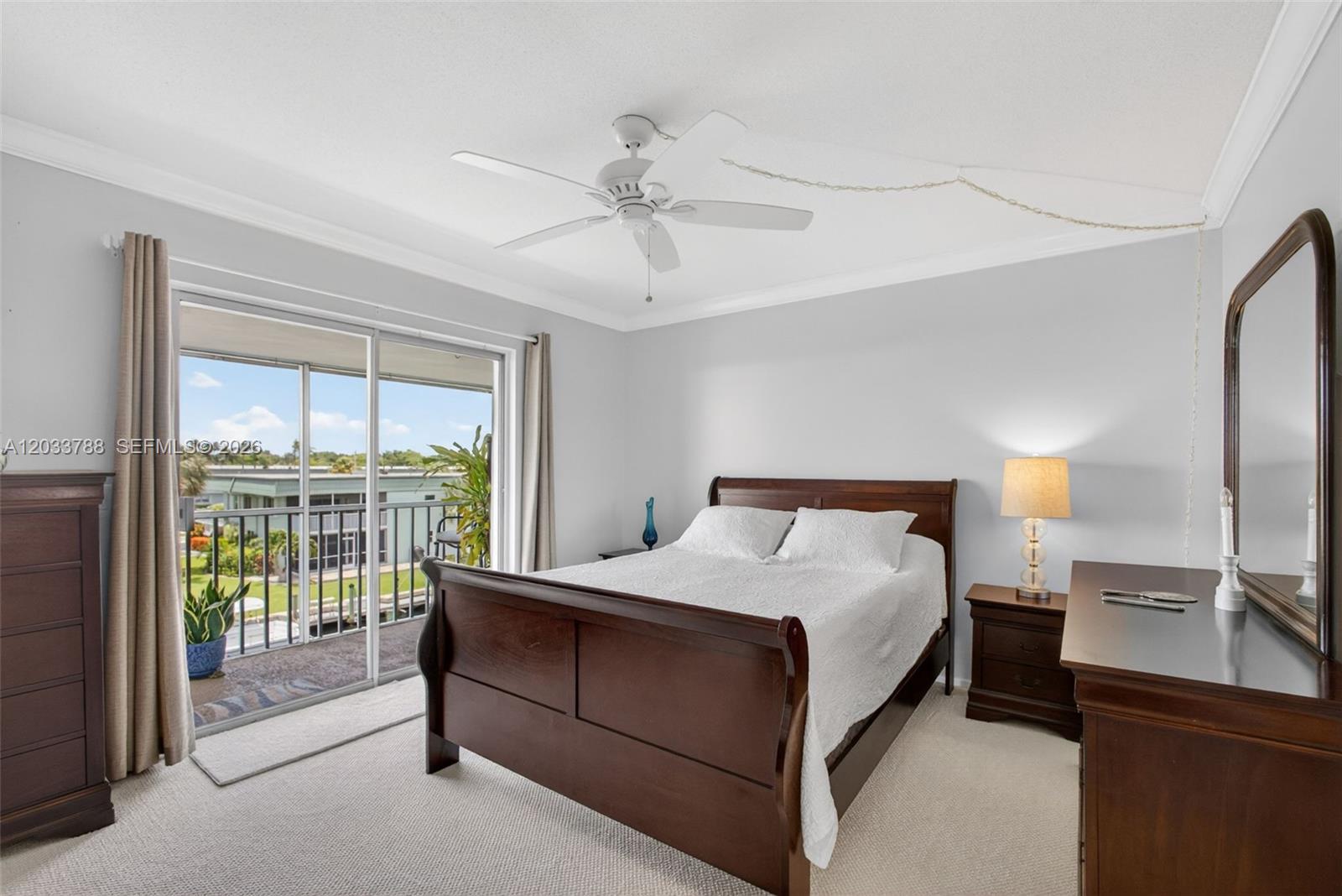 A bedroom features a wooden sleigh bed, a ceiling fan, and a sliding glass door — 112 Doolen Ct # 306, North Palm Beach FL 33408, NORTH PALM BEACH, FL