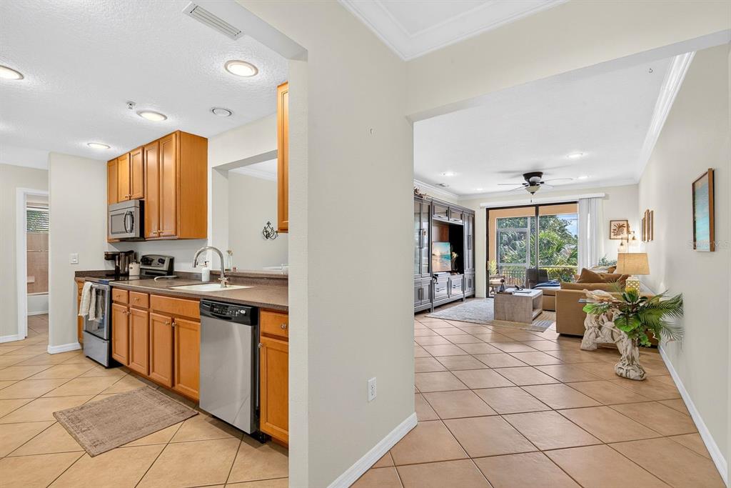 A kitchen with wood cabinets and tile floors opens into a living room with balcony access — 7228 HAMILTON ROAD UNIT 7228, BRADENTON, FL