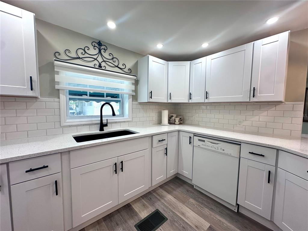A kitchen features white shaker cabinets, white subway tile backsplash, and a black sink — 1100 BELCHER ROAD S UNIT 498, LARGO, FL