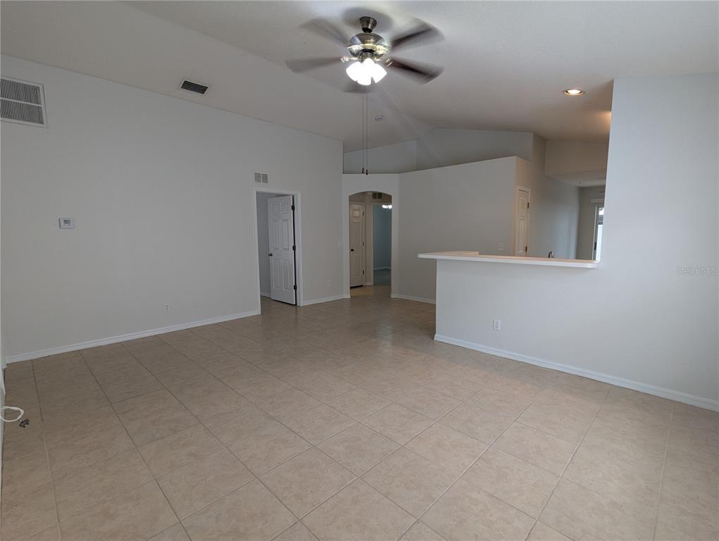 An open-concept living area features light-colored tile flooring, white walls, and a ceiling fan — 5000 ANCLOTE RIVER STREET, WESLEY CHAPEL, FL