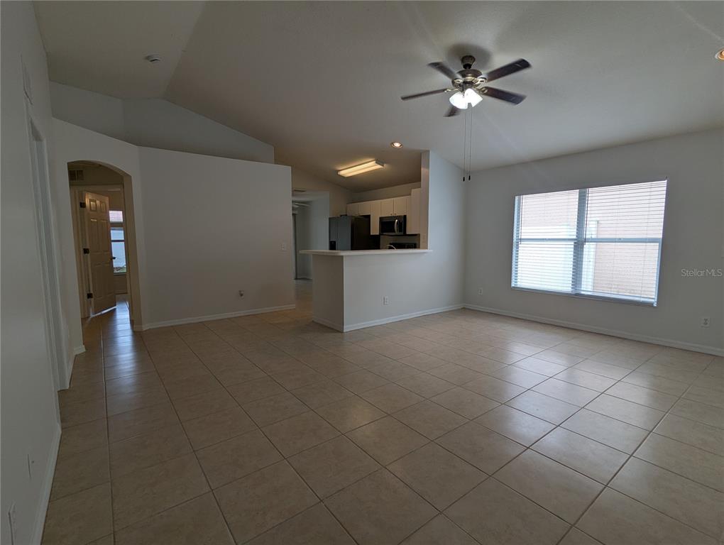 An open-concept living area with tile flooring, a ceiling fan, and a kitchen breakfast bar — 5000 ANCLOTE RIVER STREET, WESLEY CHAPEL, FL