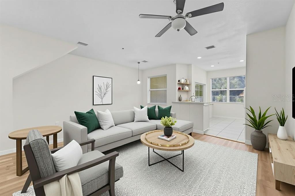 This virtually staged living room features light wood flooring, a ceiling fan, and a sectional — 3851 VIRGA BOULEVARD, SARASOTA, FL