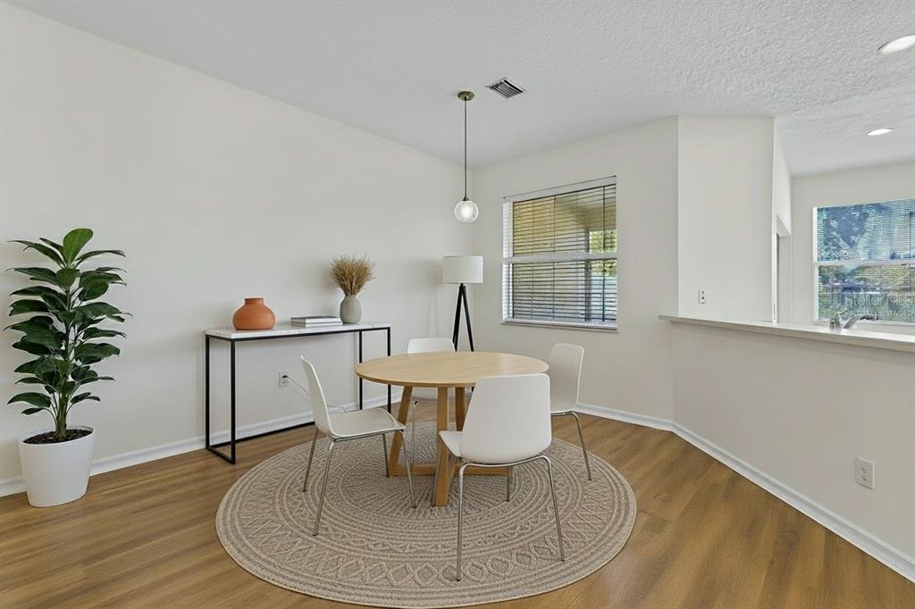 A dining area features a round wooden table, white chairs, and a circular rug — 3851 VIRGA BOULEVARD, SARASOTA, FL