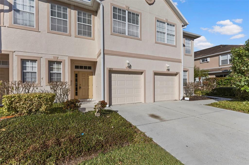 A two-story townhouse with a beige stucco exterior, two garage doors, and a front entrance — 3851 VIRGA BOULEVARD, SARASOTA, FL