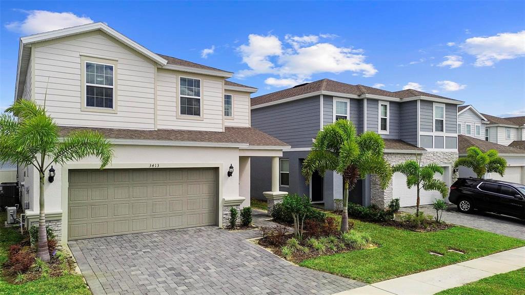 A two-story house with a paved driveway, a two-car garage, and palm trees — 3413 LILAC, DAVENPORT, FL