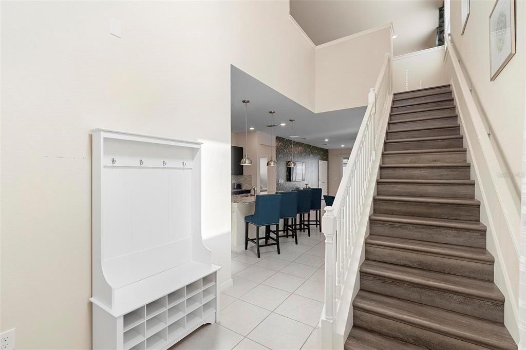 A white entryway hall features a coat rack, shoe storage, and stairs with wood treads — 3413 LILAC, DAVENPORT, FL