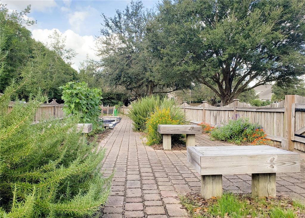 A paved garden path is lined with wooden benches, raised garden beds, and mature trees — 13660 SW 8TH AVENUE, NEWBERRY, FL