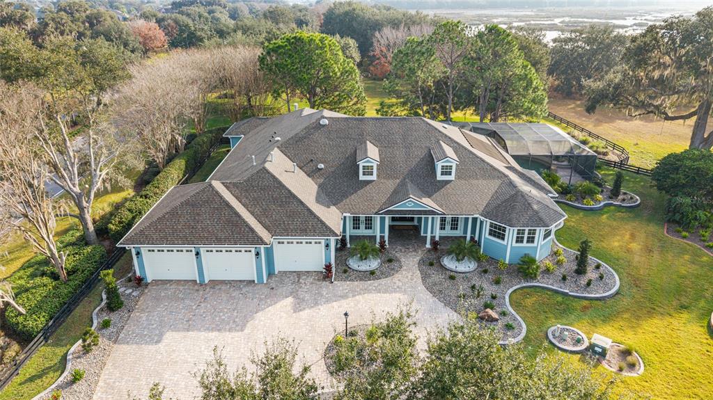 An aerial view of a blue house with a three-car garage and a screened pool — 1568 BLACK LAKE DRIVE, THE VILLAGES, FL