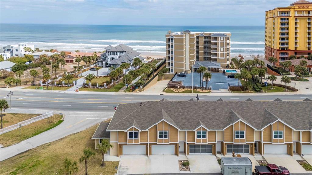 An aerial view shows a multi-unit townhouse complex situated across from beachside buildings and ocean — 108 OCEANS CIRCLE, DAYTONA BEACH, FL