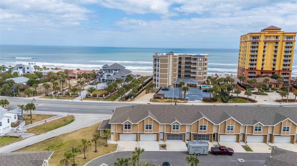 An aerial view shows a row of townhomes in the foreground facing a coastal road — 108 OCEANS CIRCLE, DAYTONA BEACH, FL