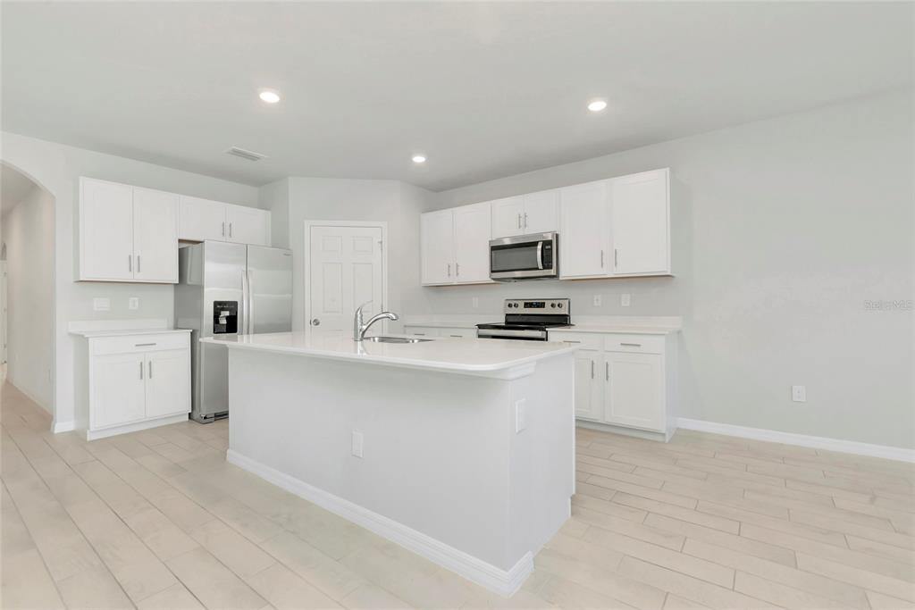 A modern kitchen features white cabinets, quartz countertops, a center island, and light-colored tile flooring — 27131 GUAPORE DRIVE, PUNTA GORDA, FL