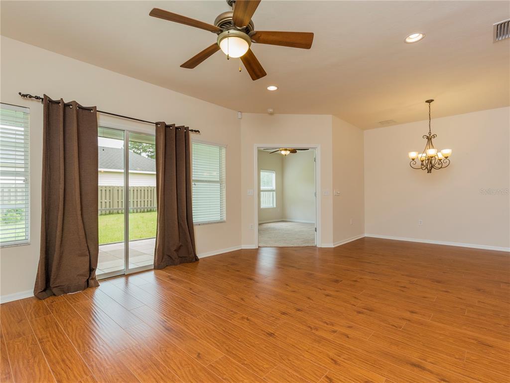 A living area with wood-look tile flooring, a ceiling fan, and a sliding glass door — 7595 SW 84TH DRIVE, GAINESVILLE, FL