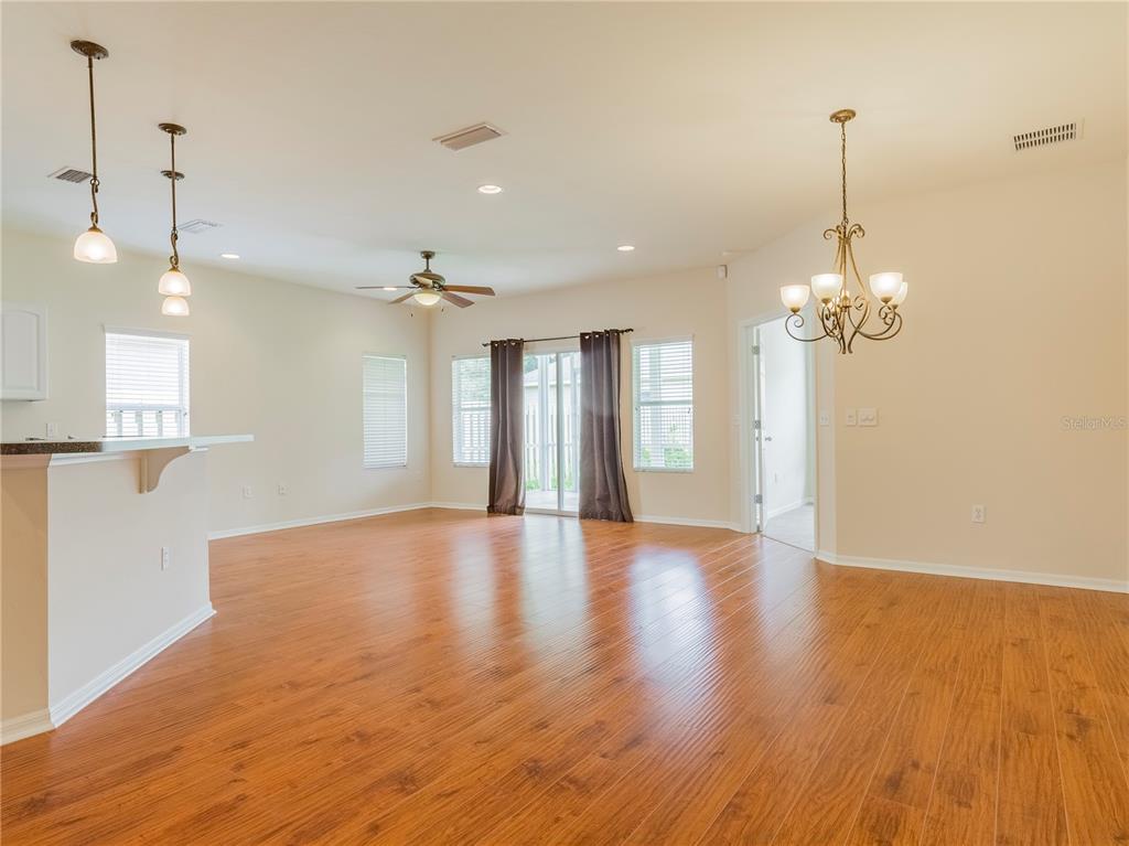 A spacious living area features wood-look flooring, a ceiling fan, and a dining chandelier — 7595 SW 84TH DRIVE, GAINESVILLE, FL