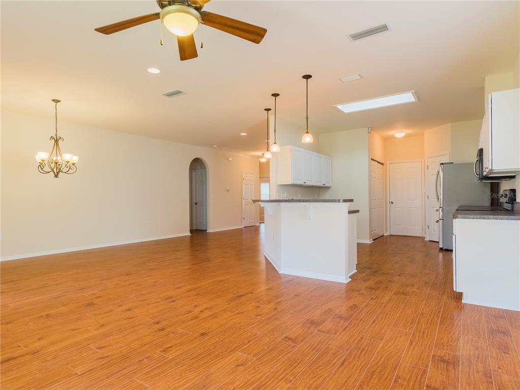 An open-concept kitchen and living area features wood-look tile flooring and a breakfast bar — 7595 SW 84TH DRIVE, GAINESVILLE, FL