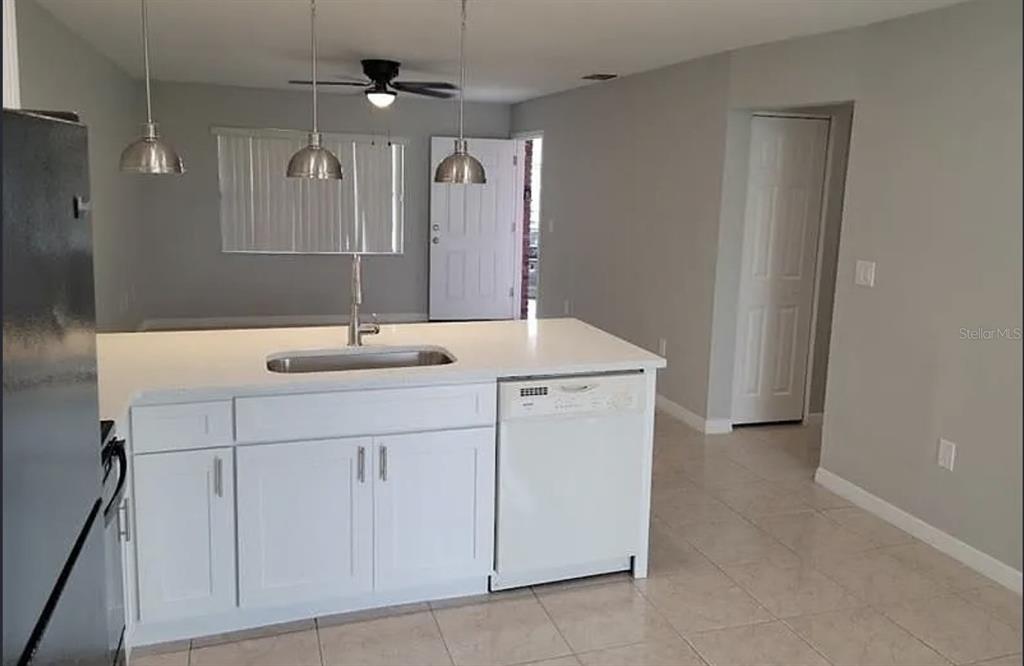A kitchen island with a sink and dishwasher sits in front of a dining area — 783 SQUIRREL COURT UNIT B, KISSIMMEE, FL