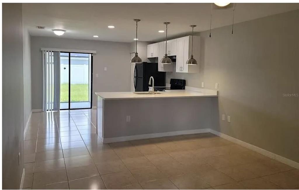 A kitchen with white cabinets and a breakfast bar overlooks a tiled dining area — 783 SQUIRREL COURT UNIT B, KISSIMMEE, FL