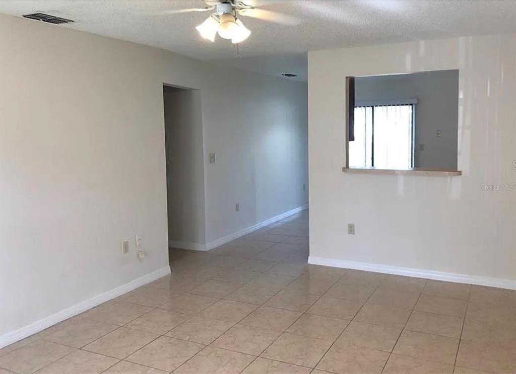 An interior view of a room with beige tile flooring, light walls, and a ceiling fan — 783 SQUIRREL COURT UNIT B, KISSIMMEE, FL