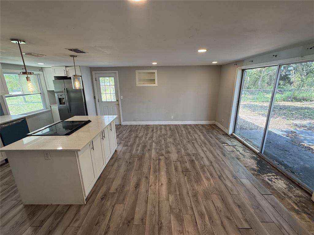A kitchen with a central island, stainless steel refrigerator, and wood-look flooring near sliding doors — 10015 PREVATT STREET, GIBSONTON, FL