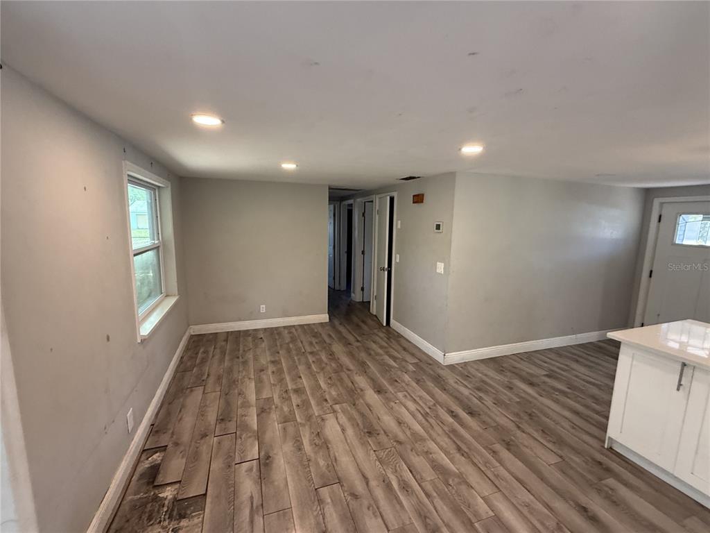 An interior view of a room with gray walls, recessed lighting, and wood-look flooring — 10015 PREVATT STREET, GIBSONTON, FL