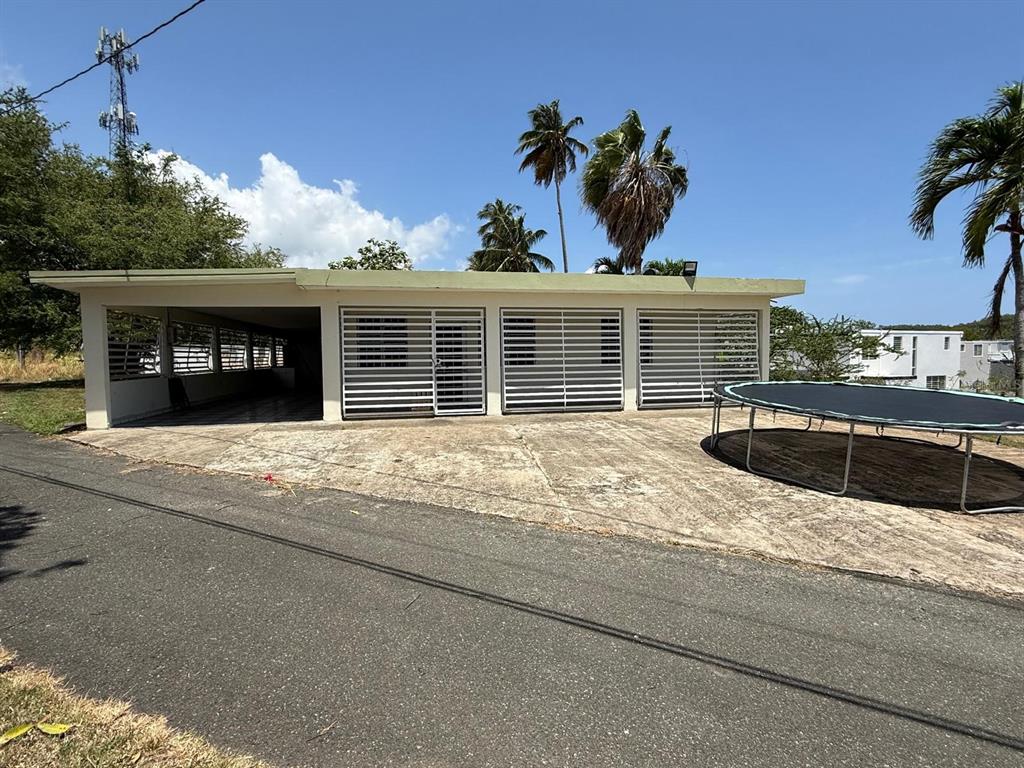 A single-story house with a carport, white security shutters, and a trampoline on the concrete driveway — Carr 686 Km 0.2 CARR 686 KM 0.2 BO COTO NORTE SECTOR GUAYANEY, MANATI, PR