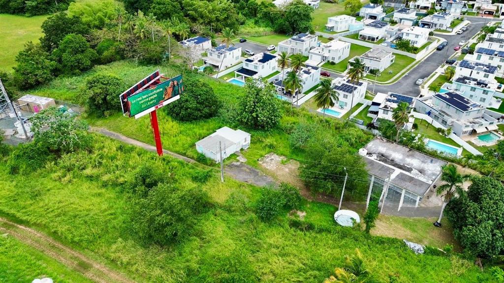 An aerial view shows a billboard, a small house, and a residential neighborhood with pools — Carr 686 Km 0.2 CARR 686 KM 0.2 BO COTO NORTE SECTOR GUAYANEY, MANATI, PR