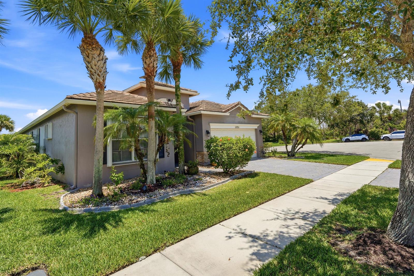 A single-story house with a paved driveway, palm trees, and a landscaped front yard — 11031 SW Dunhill Court, FL 34987, FL