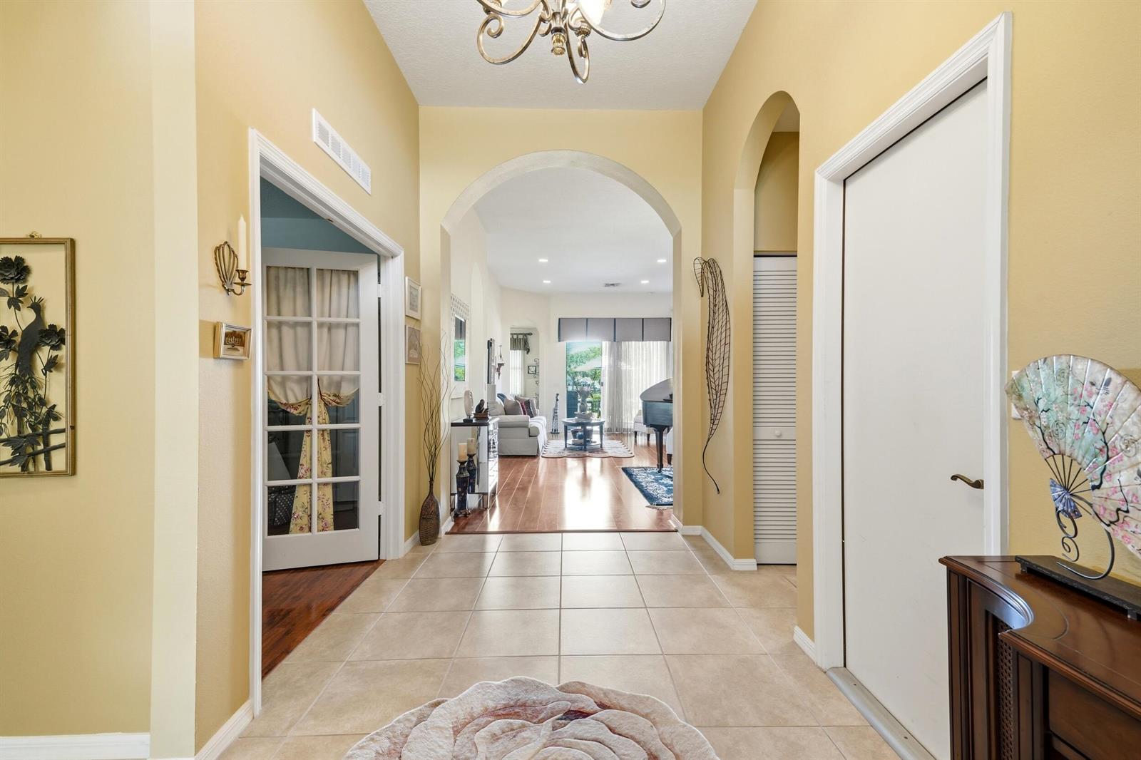 A tiled foyer leads through an arched doorway into a living area with hardwood floors — 11031 SW Dunhill Court, FL 34987, FL